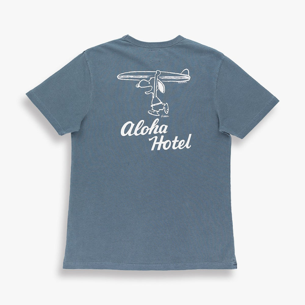 Gray shirt a design of snoopy holding a surfboard over his head. The words aloha hotel written underneath it in white