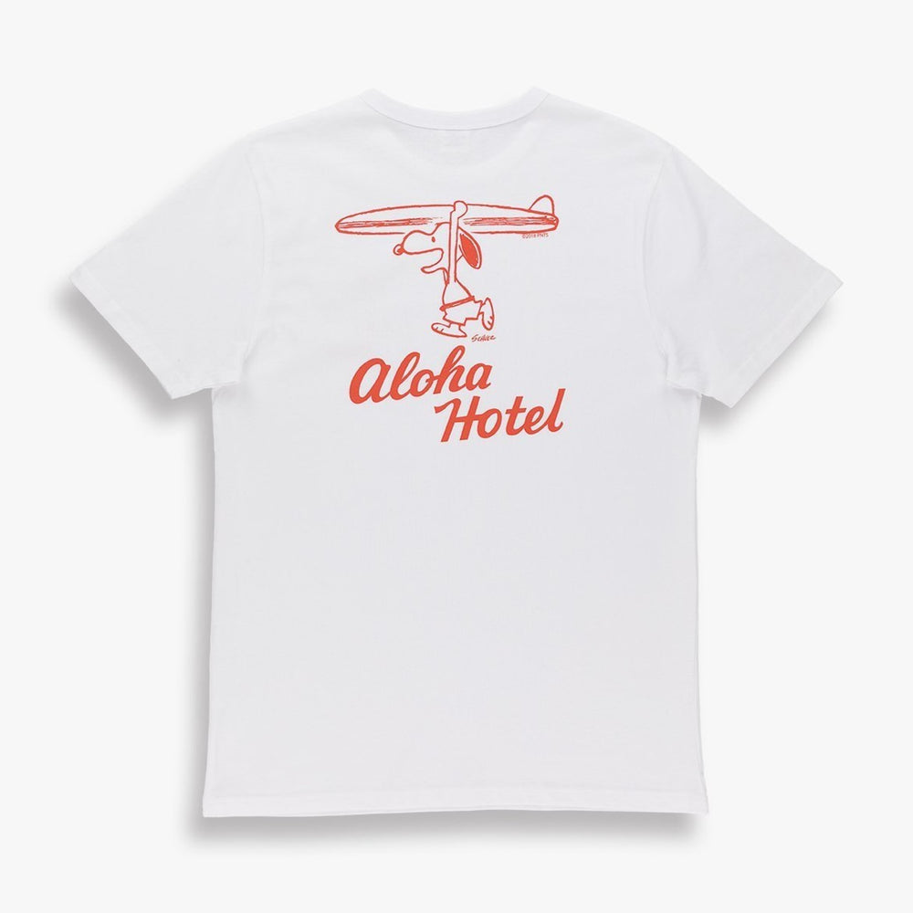 White shirt with a design of snoopy holding a surfboard over his head. The words aloha hotel written underneath it in red. 