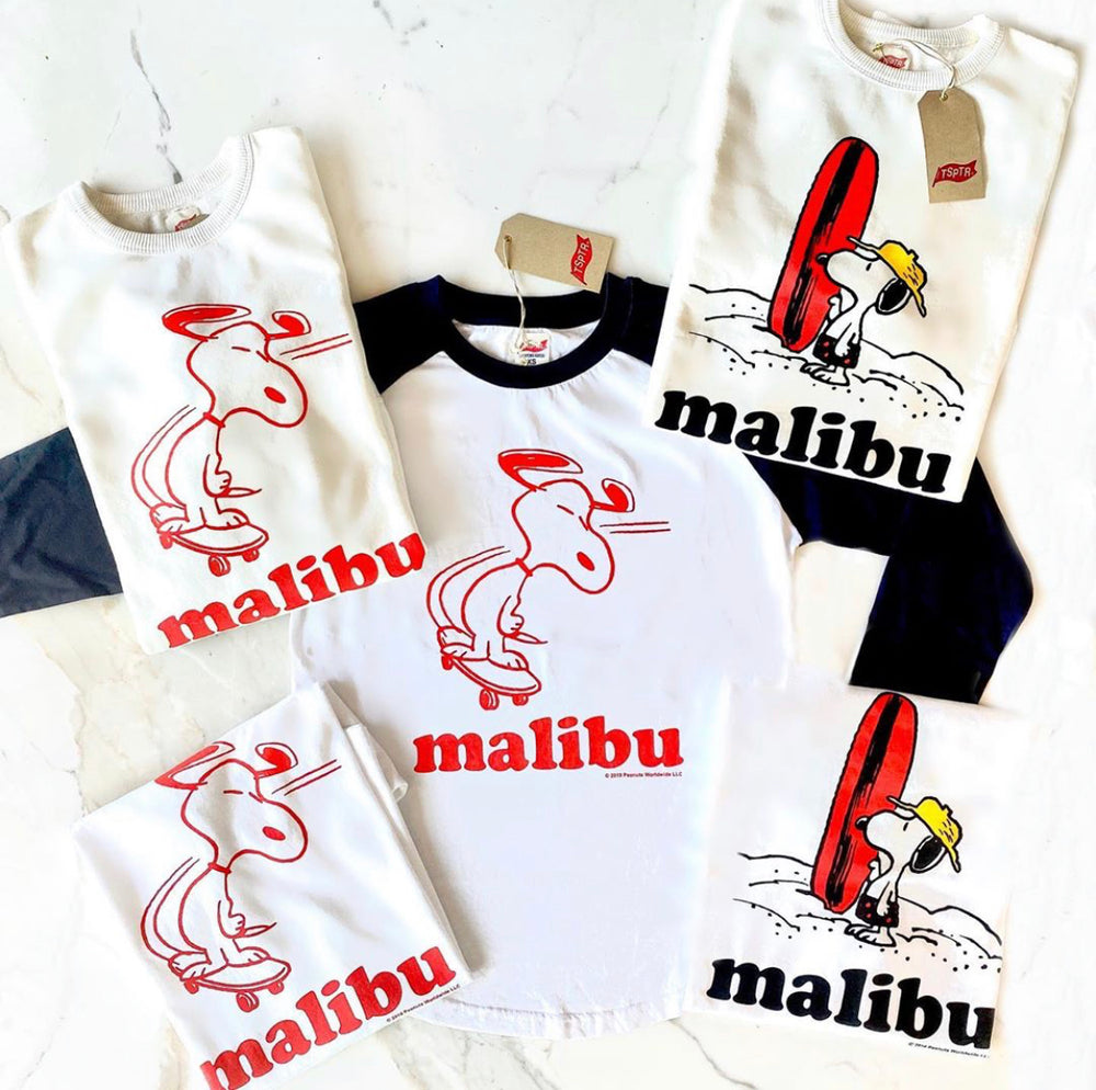 TSPTR Malibu Skate Raglan. White shirt with black sleeves. Red design of Snoopy riding a skateboard on the front. 