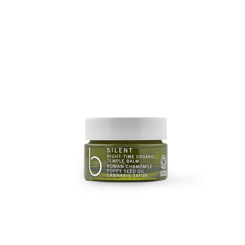 A small green translucent canister with a white twist on lid. On it says silent night-time oorganic temple balm. Roman chamomile poppy seed oil. Cannabis sative. Our organic night-time temple balm contains poppy seed oils, known for their relaxing properties. Combined with a blend of roman chamomile, lavender flower and vetiver root essential oils. Sleep peacefully and wake restored.
