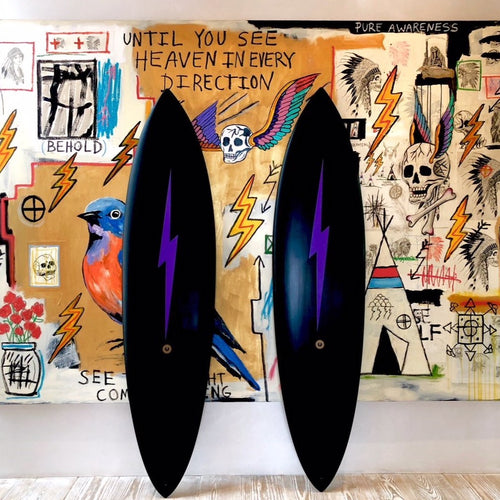 Two all black surfboards with a purple lightning bolt down the middle. 