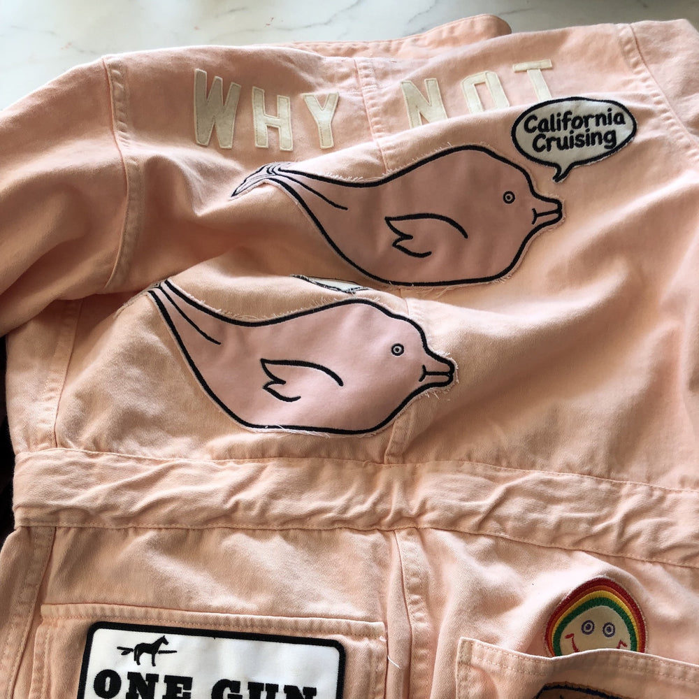 MOMO X One Gun Pink Jumpsuit in pink with multiple patches in the sleeve and the front pocket.