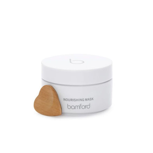 A white canister with a white twist on lid. It says Bamford Nourishing mask on it. A deeply hydrating treatment mask with powerful anti-ageing actives. Within a nourishing base of organic shea butter and coconut oil, soy stem cells help boost the production of collagen and elastin to promote youthful skin.