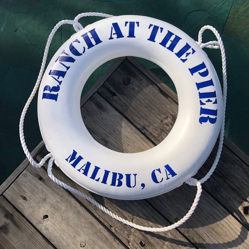 A white lifesaver with Ranch at the Pier Malibu, CA written in blue text. 