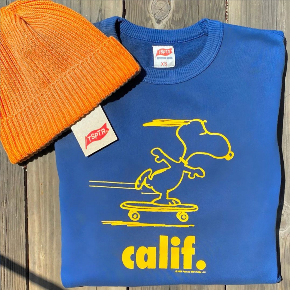 Blue Peanuts Calif Pullover with a yellow design of snoopy skateboarding