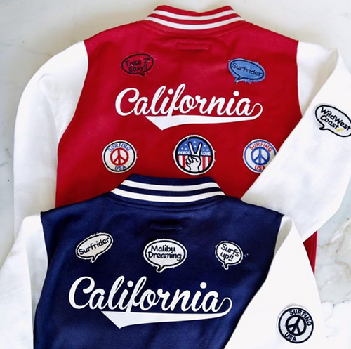 On The Rise California Varsity Jacket. One is red with white sleeves, the other is blue with white sleeves. On the back it says California in white cursive text and patches surrounding it. 