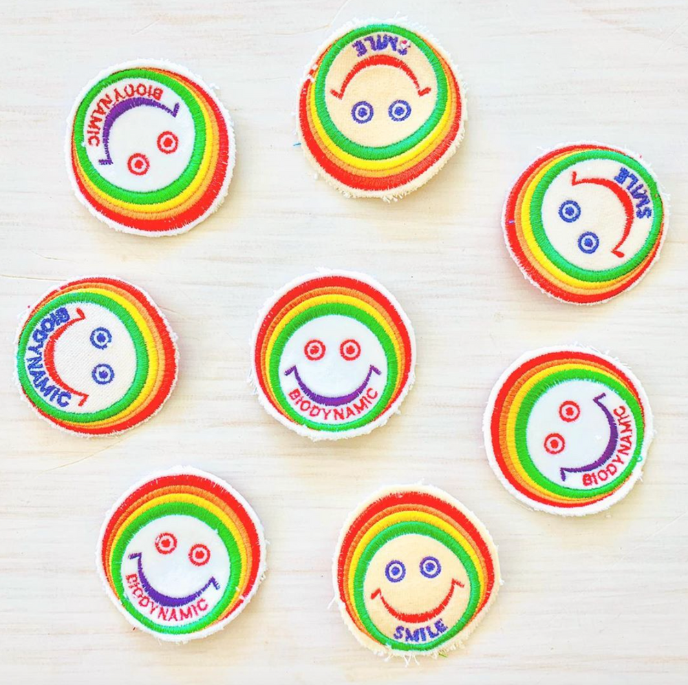 Recycled Cashmere Patch with a smiley face outlined in a rainbow pattern. 