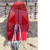 Harbour Surfboard. Red surfboard with a black stripe down the middle.  The fnin is red and the strap is white. 