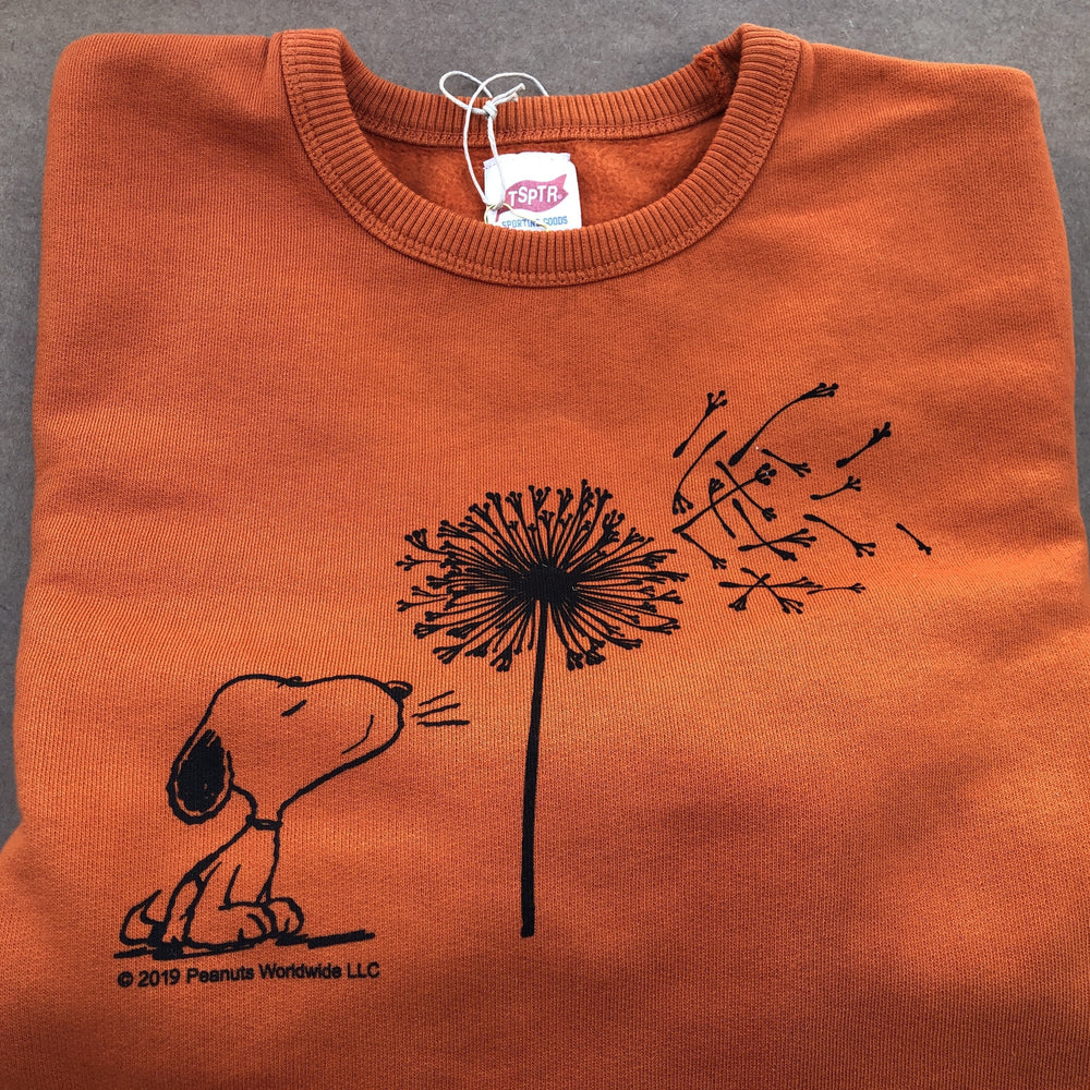 TSPTR My Reality Pullover. Orange sweater with a design of Snoopy blowing a dandelion flower. 