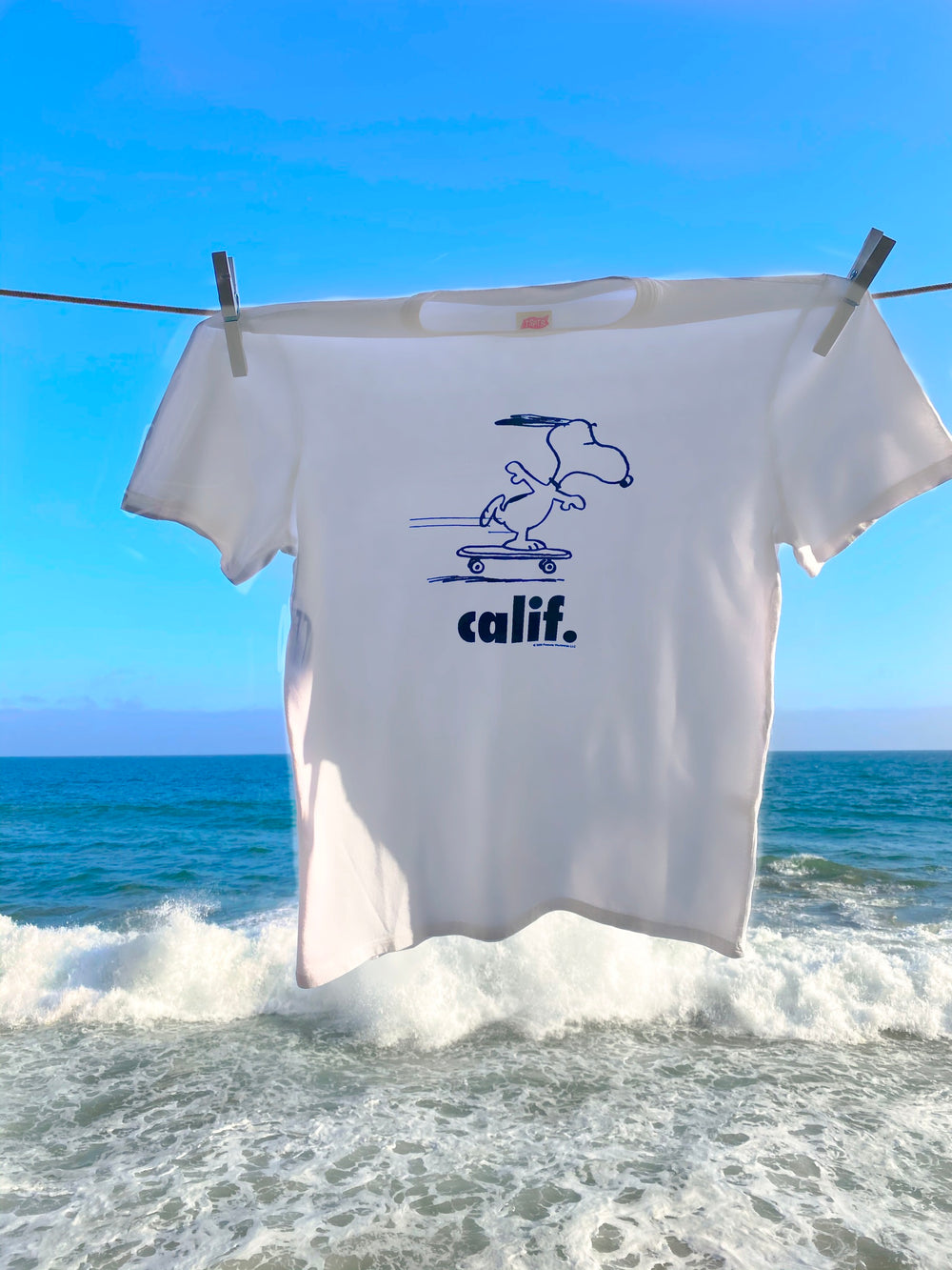 White  Peanuts Calif T-Shirt with a design of snoopy skateboarding.